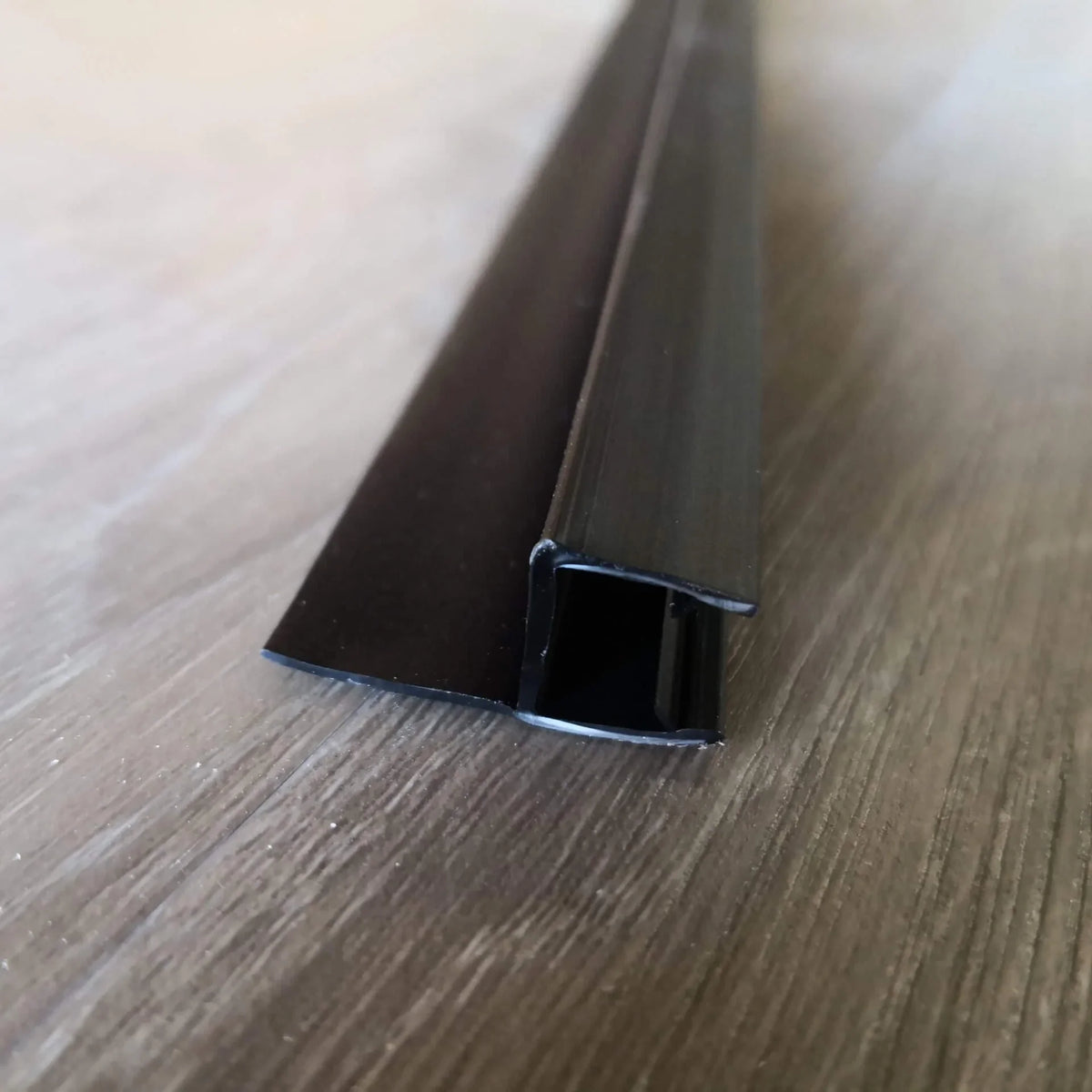 End view of the black shower door side seal profile and glass channel